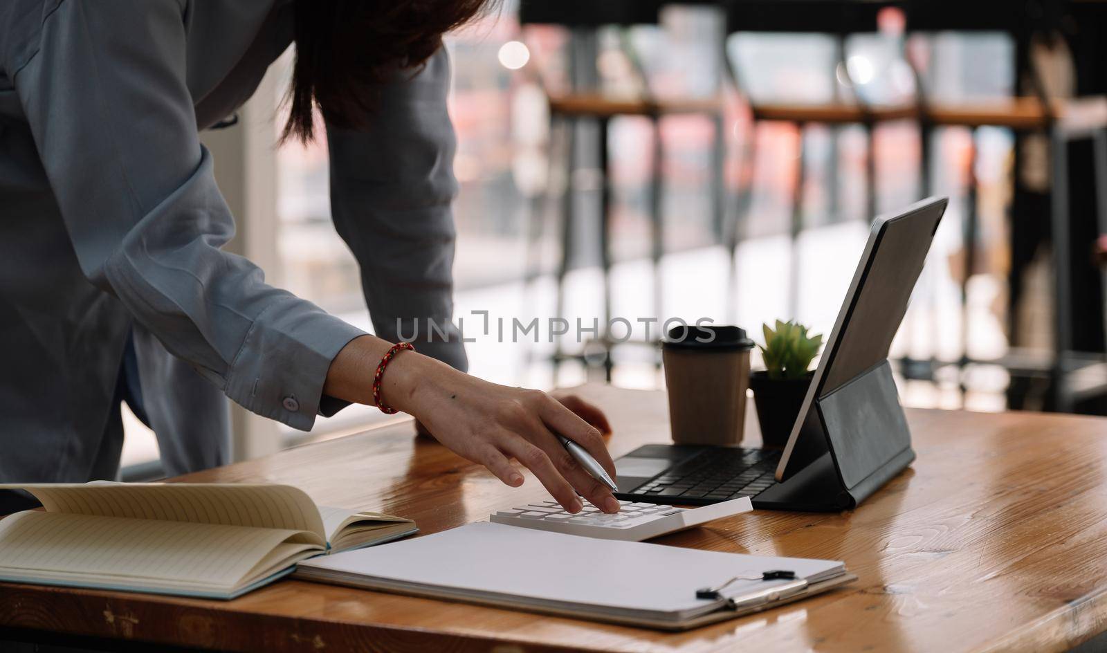 businesswoman working on desk office with using a calculator to calculate the numbers, finance accounting concept