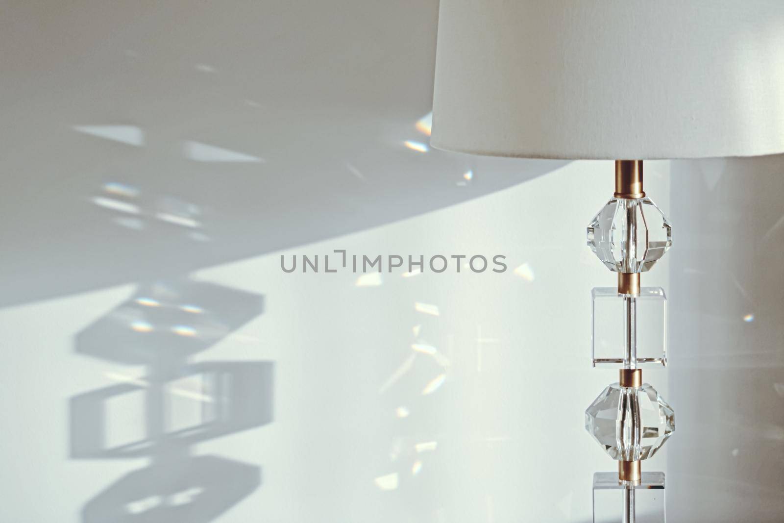 Gold and crystal details of a bedside lamp with shadows at sunset, luxury home decor closeup