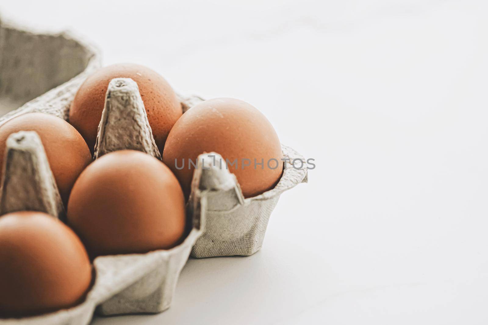 organic eggs in egg box on white marble kitchen table by Anneleven