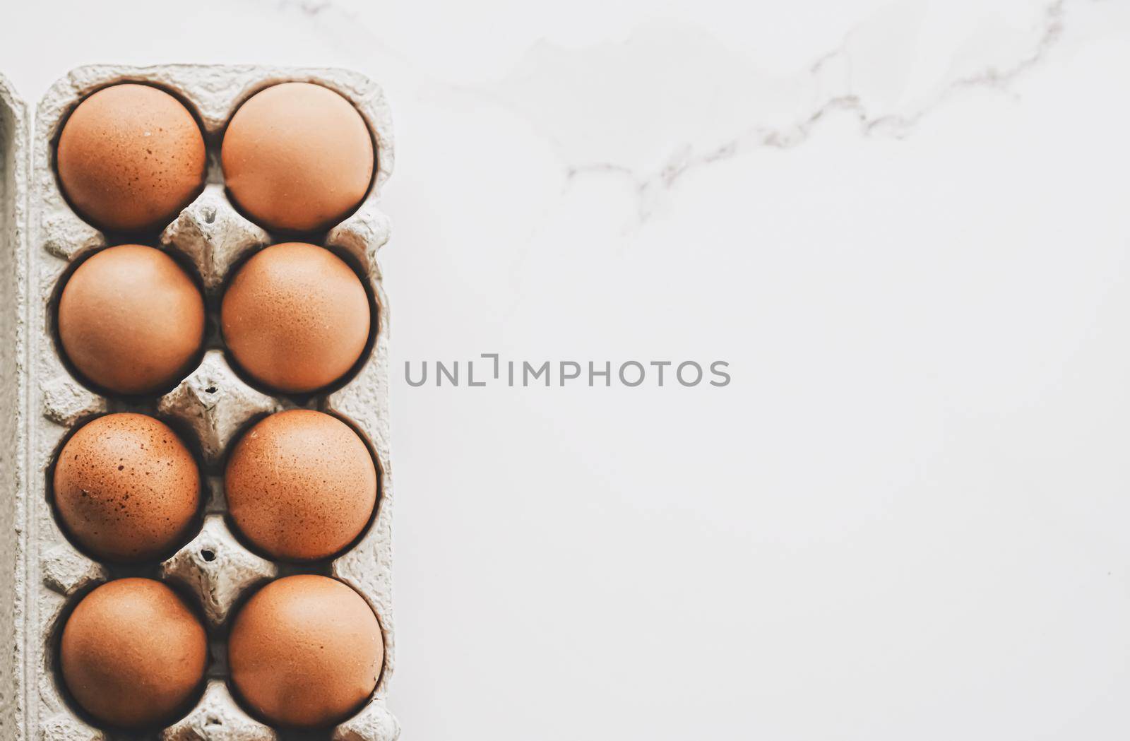 organic eggs in egg box on white marble kitchen table, closeup