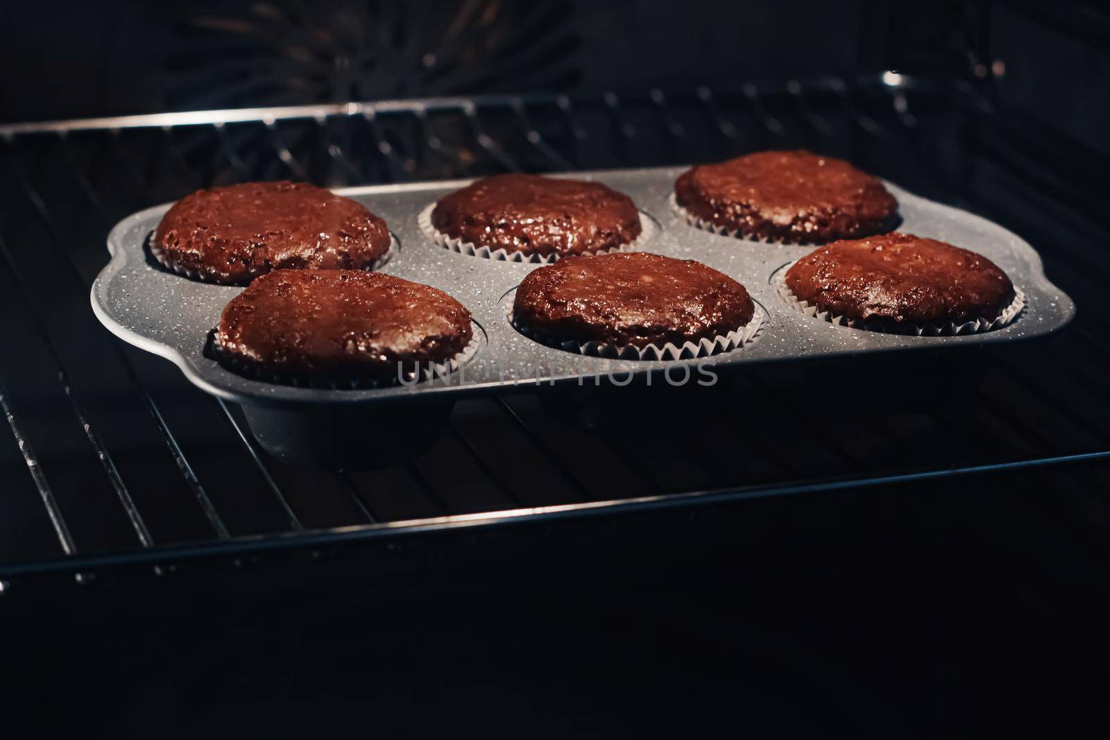 Chocolate muffins baking in the oven, homemade comfort food recipe by Anneleven