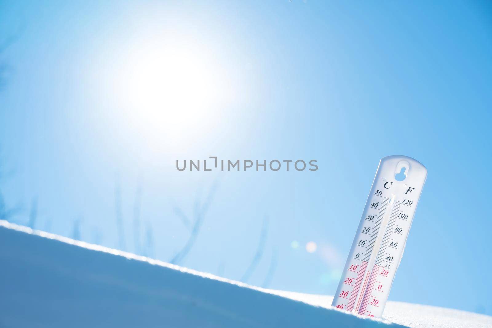 The thermometer lies on the snow and shows a negative temperature in cold weather on the blue sky.Meteorological conditions with low air and ambient temperatures.Climate change and global warming