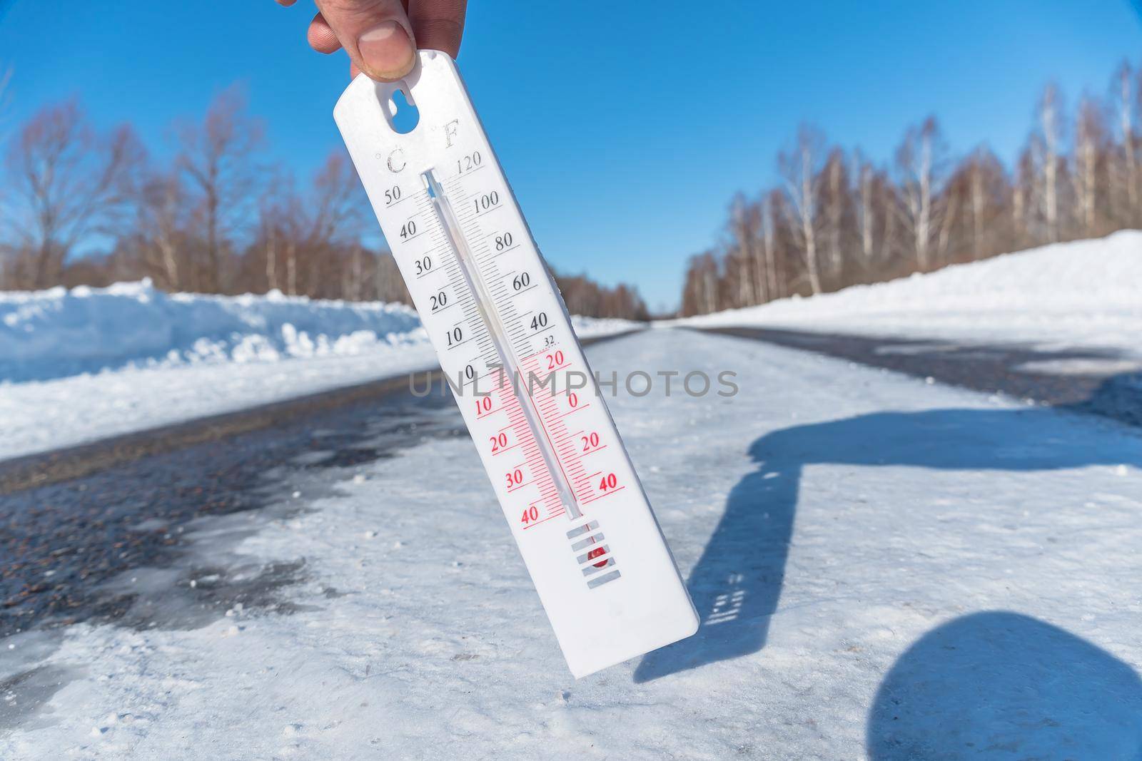 The thermometer shows a negative temperature in cold weather against the background of an icy road or highway.Poor weather conditions with low temperatures and ice.An icy snow-covered road or speedway by YevgeniySam