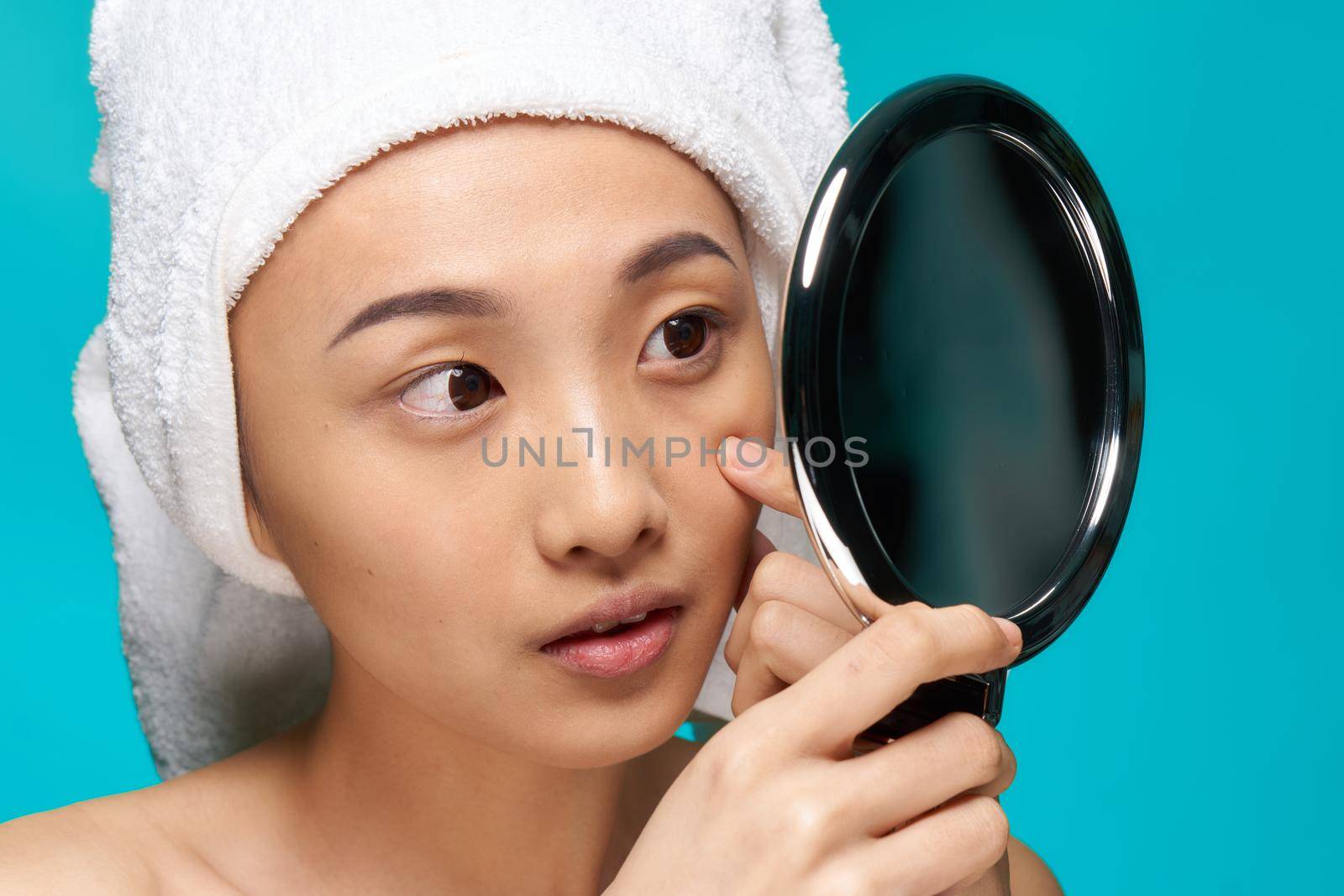 pretty woman naked shoulders towel on head mirror in hands close-up clean skin. High quality photo