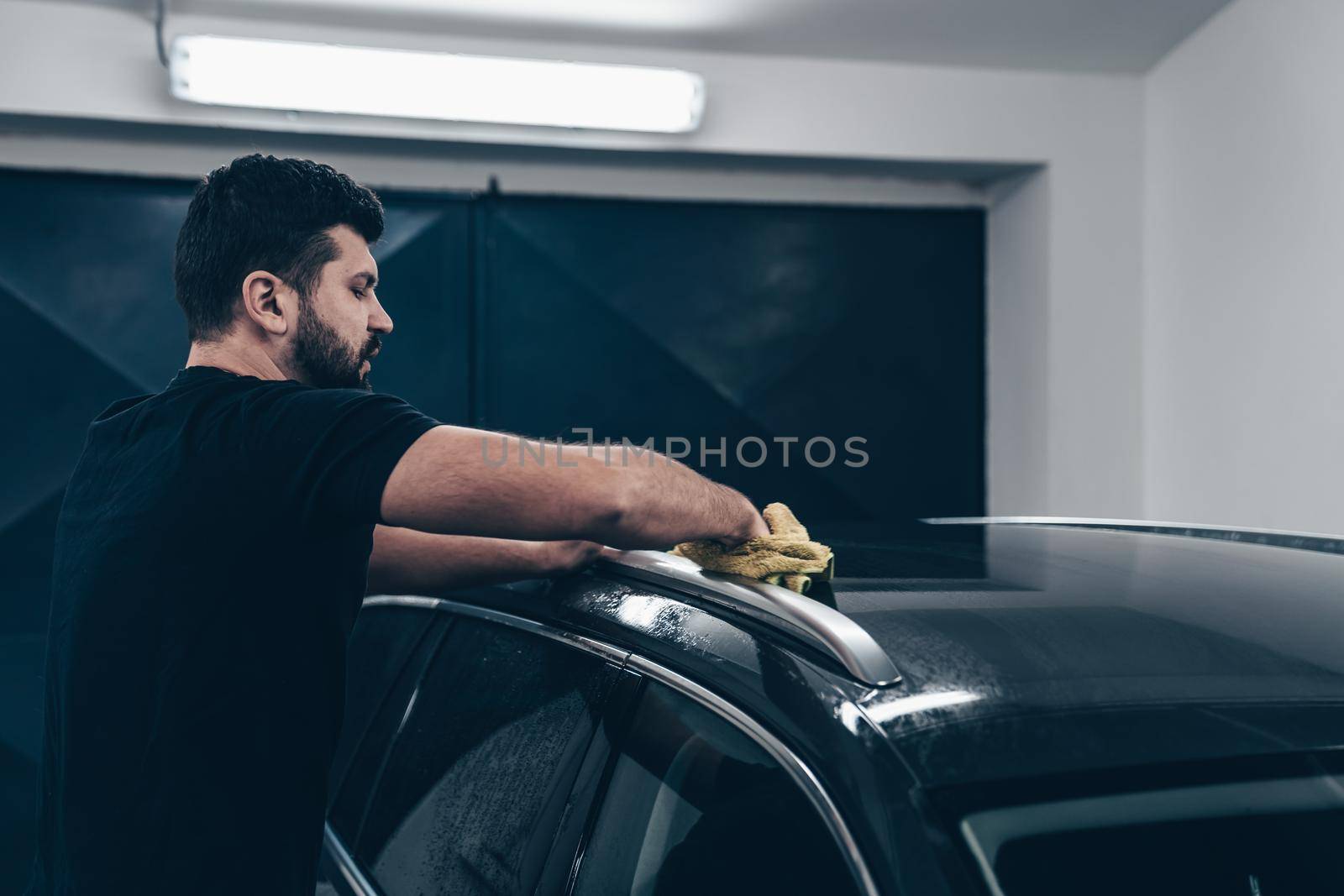 man cleans the car body with a towel. auto care.