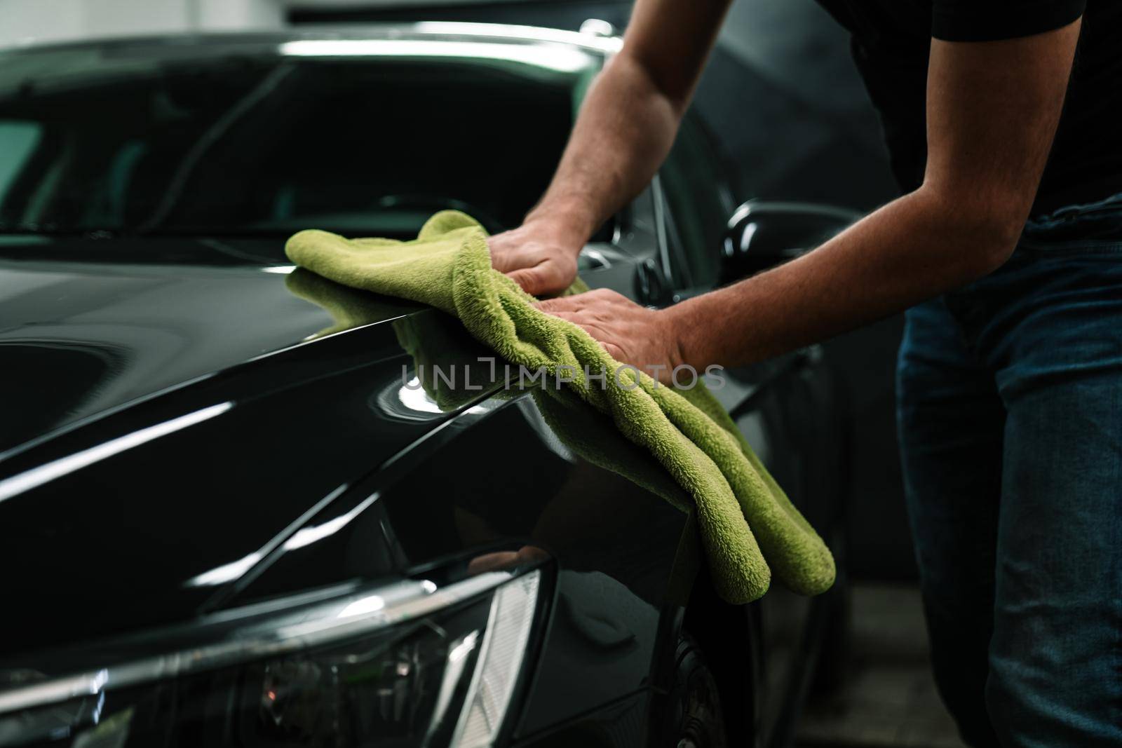 man cleans the car body with a towel. auto care.