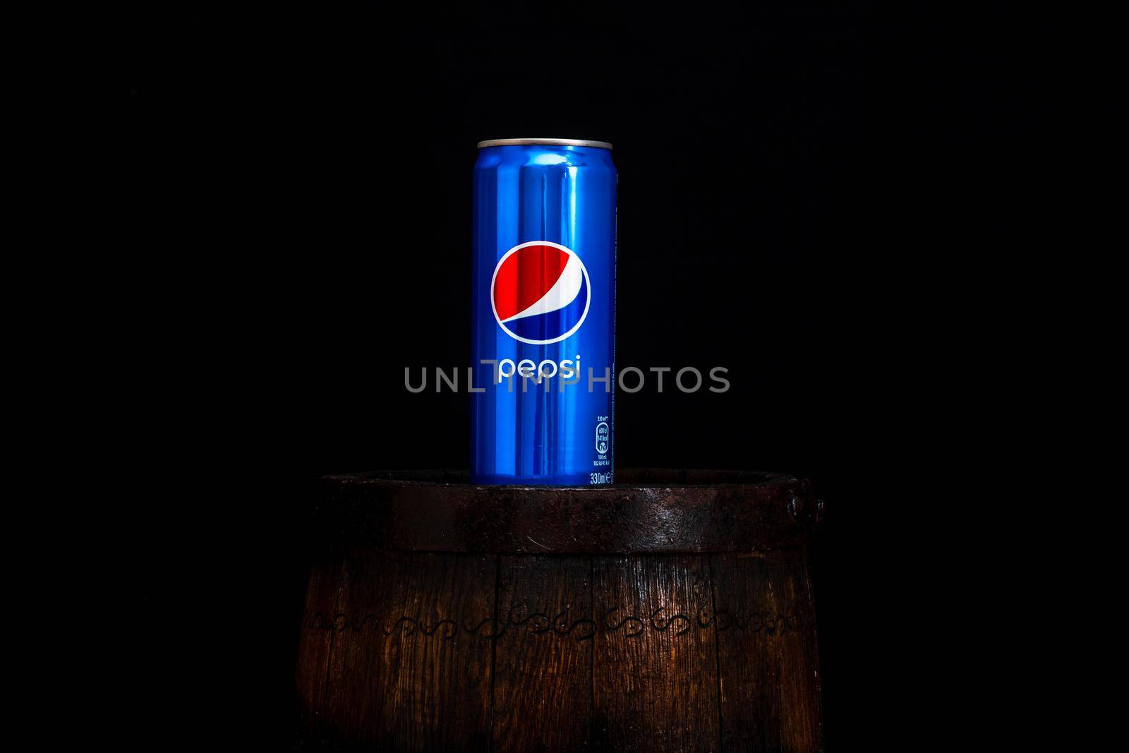 Can of Pepsi Cola on wooden barrel with dark background. Illustrative editorial photo Bucharest, Romania, 2021 by vladispas