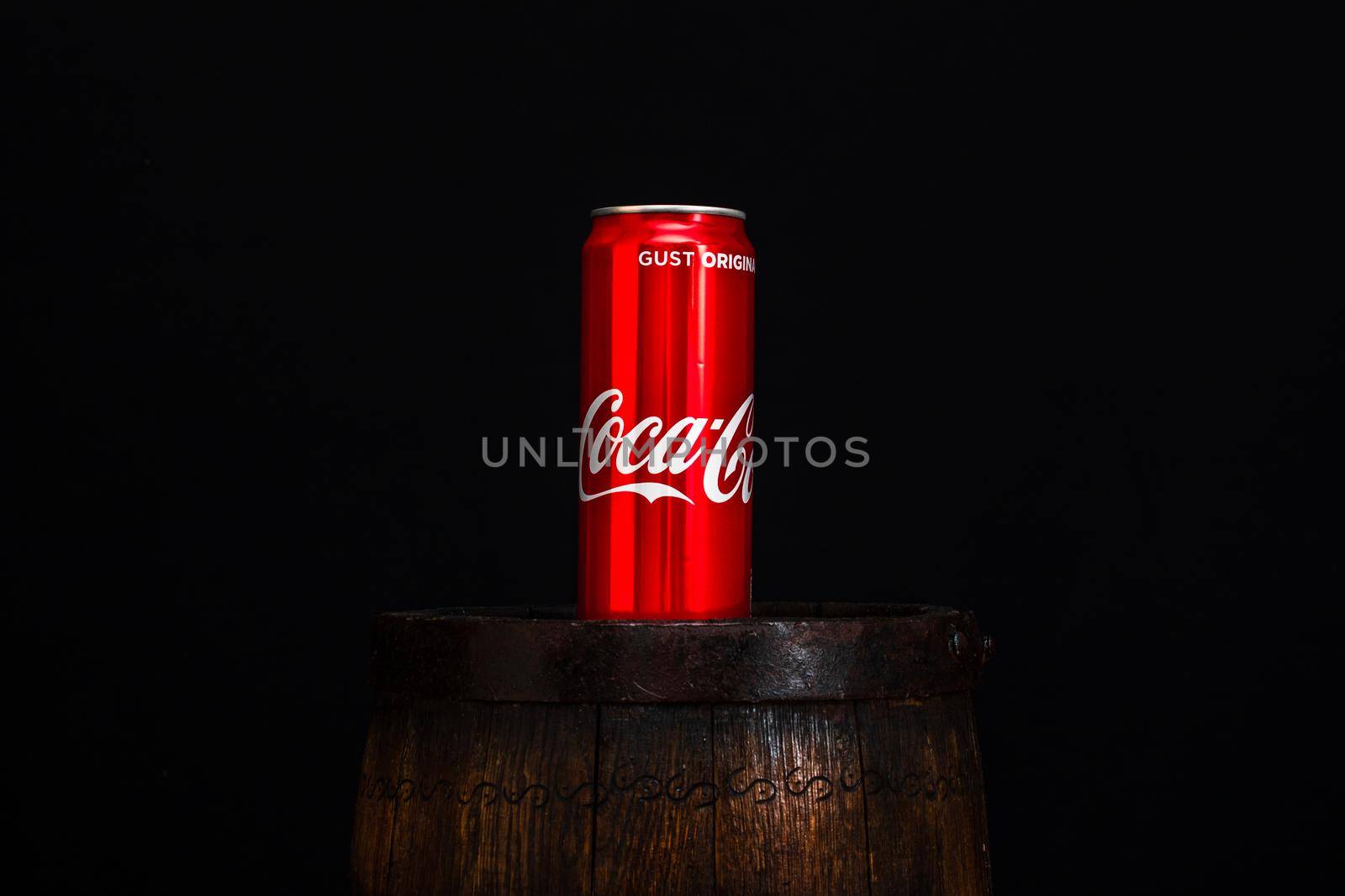 Can of Coca Cola on wooden barrel with dark background. Illustrative editorial photo Bucharest, Romania, 2021 by vladispas