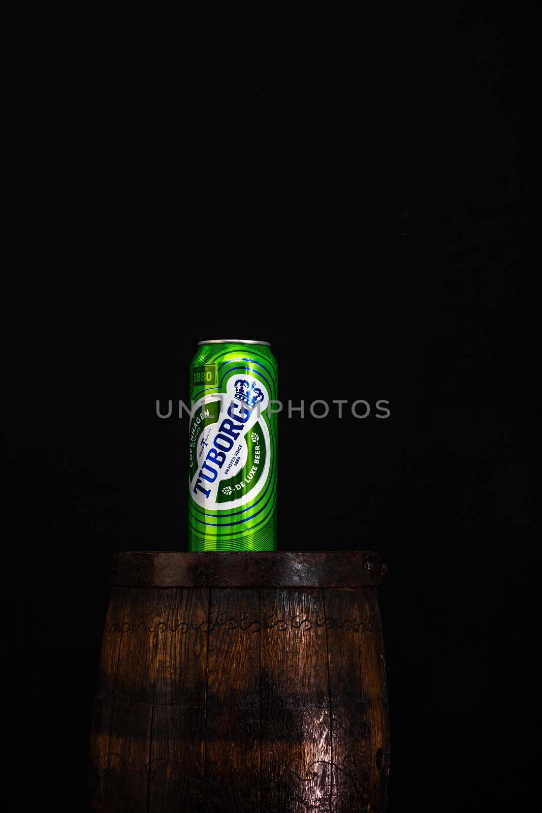 Can of Tuborg beer on beer barrel with dark background. Illustrative editorial photo Bucharest, Romania, 2021 by vladispas