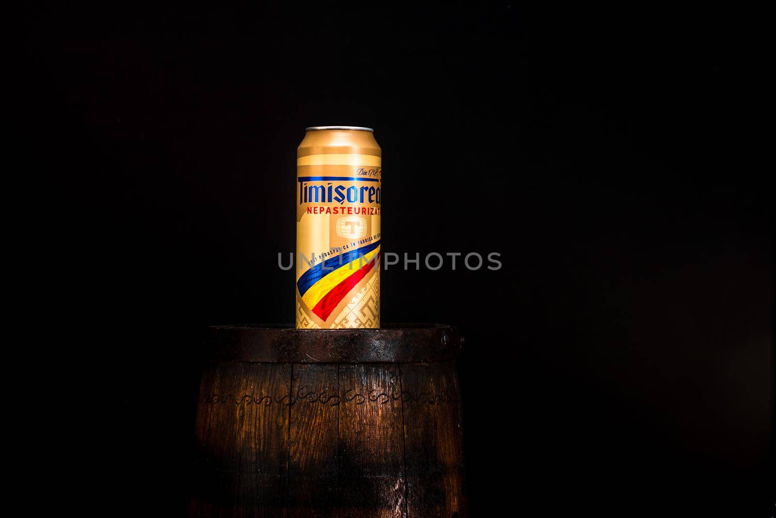 Can of Timisoreana beer on beer barrel with dark background. Illustrative editorial photo shot in Bucharest, Romania, 2021