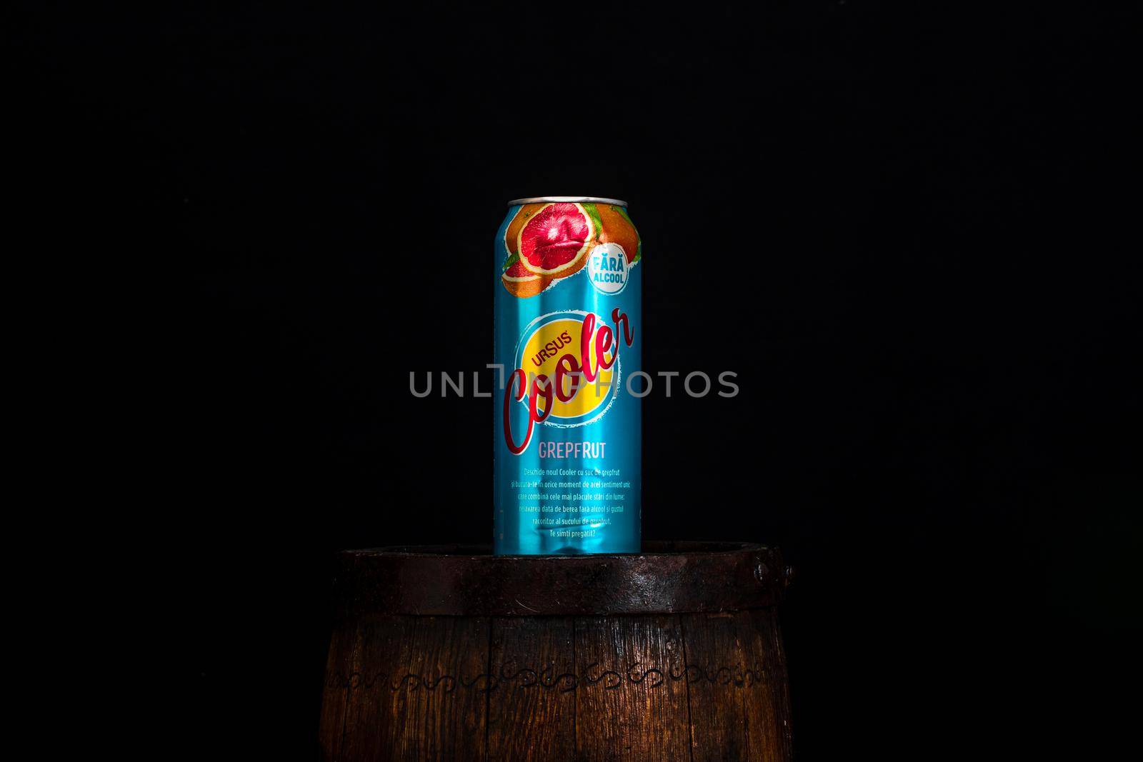 Can of Ursus Cooler beer on beer barrel with dark background. Illustrative editorial photo shot in Bucharest, Romania, 2021