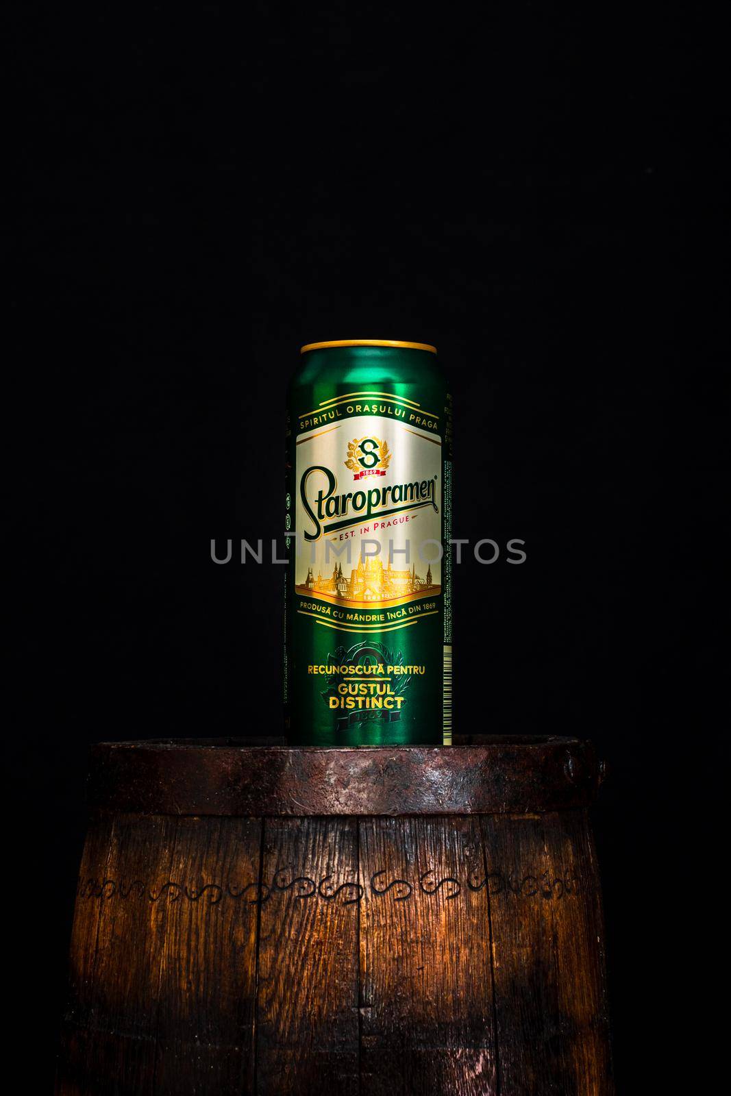 Can of Staropramen beer on beer barrel with dark background. Illustrative editorial photo shot in Bucharest, Romania, 2021 by vladispas