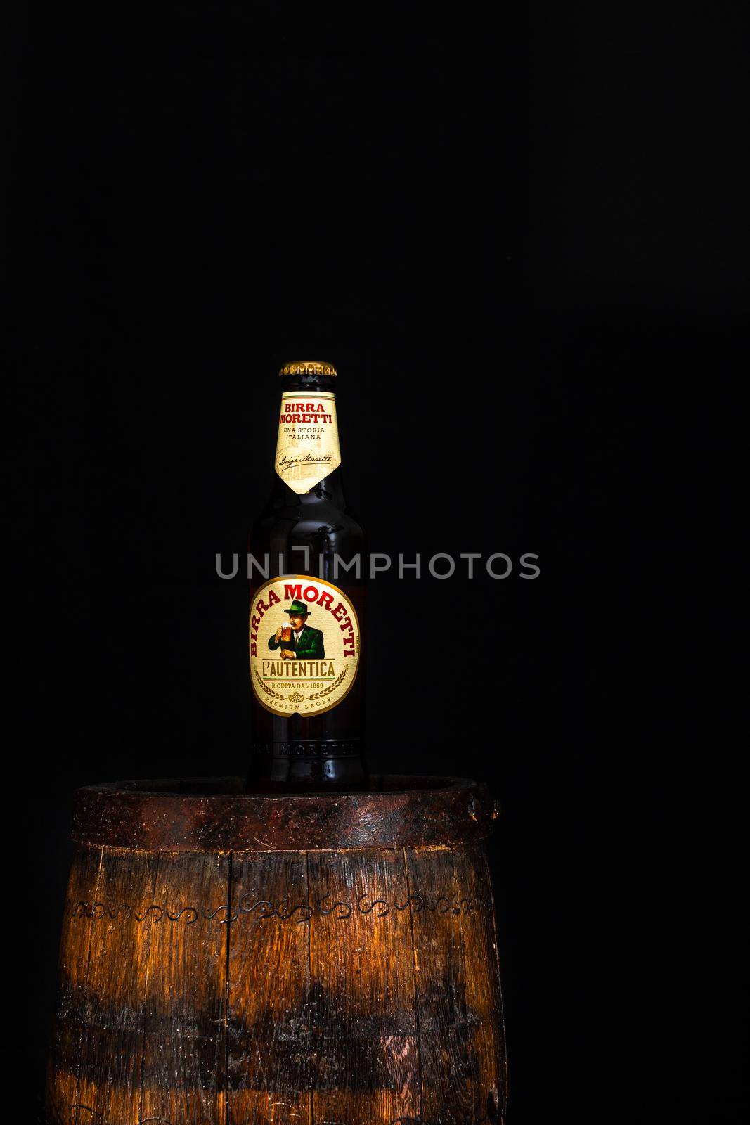 Bottle of Birra Moretti beer on wooden barrel with dark background. Illustrative editorial photo Bucharest, Romania, 2021