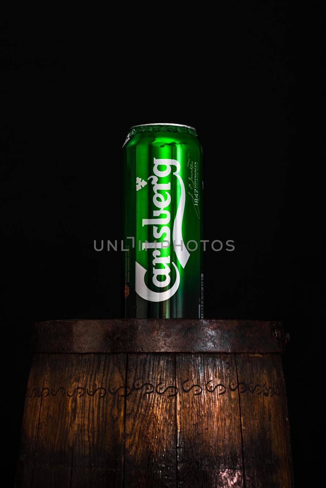 Can of Carsberg beer on beer barrel with dark background. Illustrative editorial photo shot in Bucharest, Romania, 2021 by vladispas