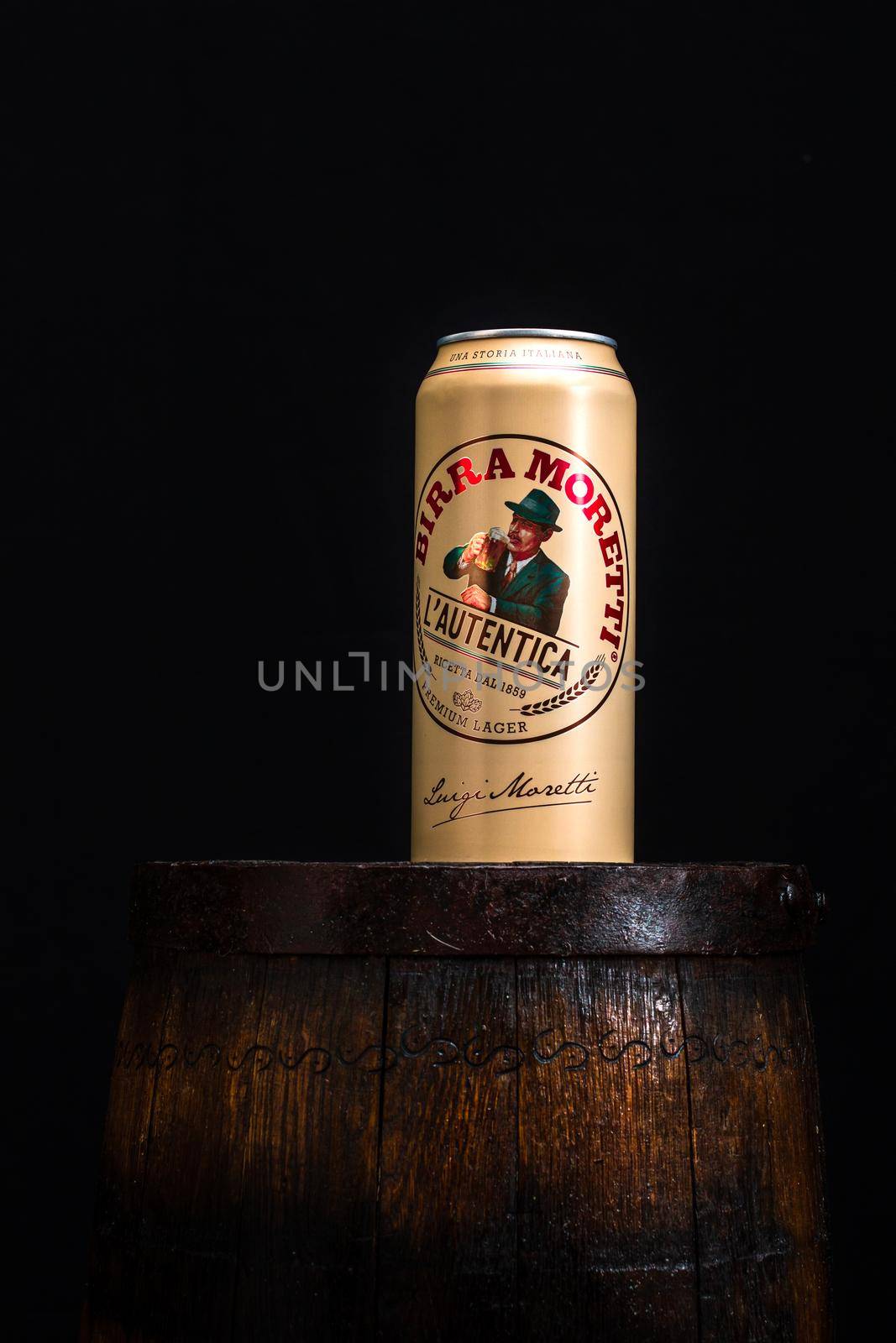 Can of Birra Moretti beer on wooden barrel with dark background. Illustrative editorial photo Bucharest, Romania, 2021 by vladispas
