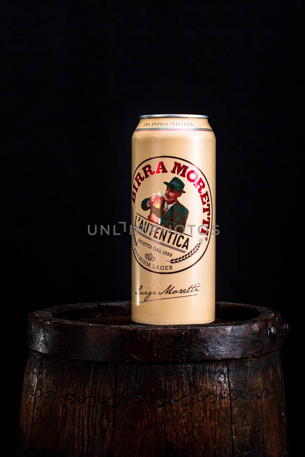 Can of Birra Moretti beer on wooden barrel with dark background. Illustrative editorial photo Bucharest, Romania, 2021 by vladispas