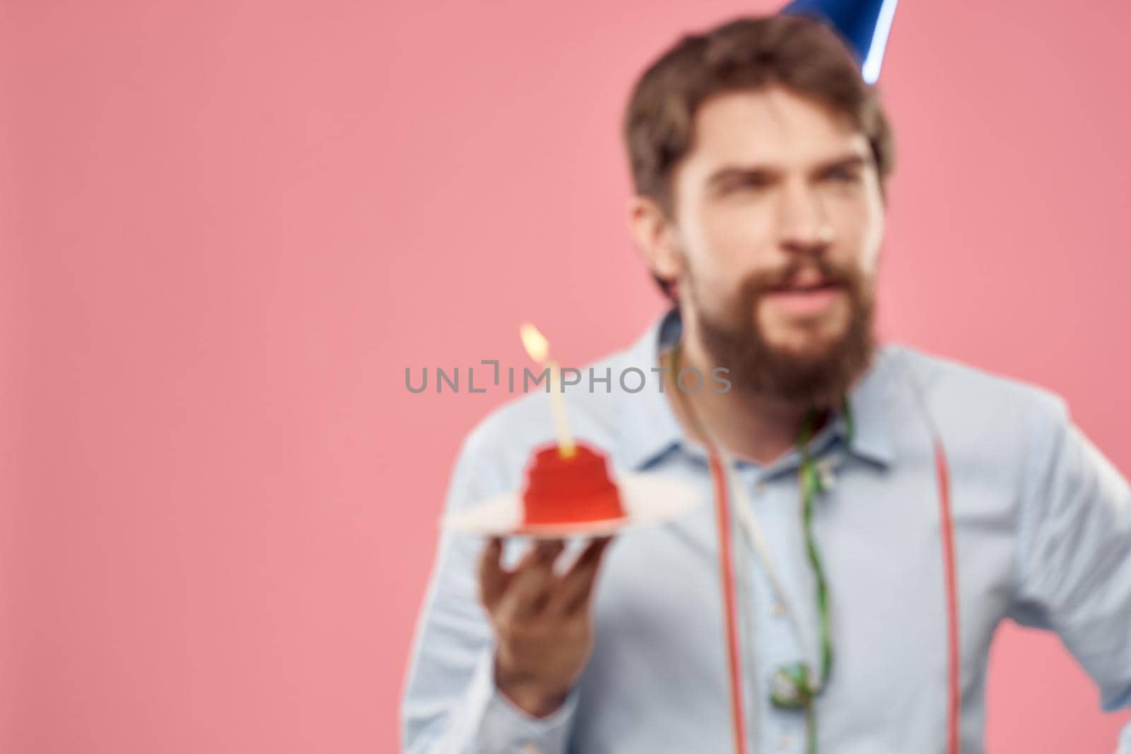 Birthday of a man with a cake and with a candle on a pink background. High quality photo