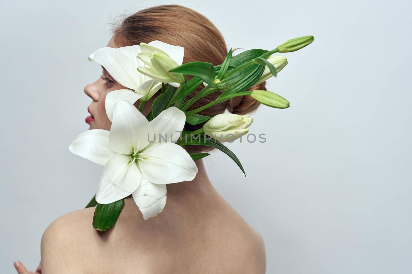Lady with a bouquet of white flowers on a gray background portrait cropped view close-up by SHOTPRIME
