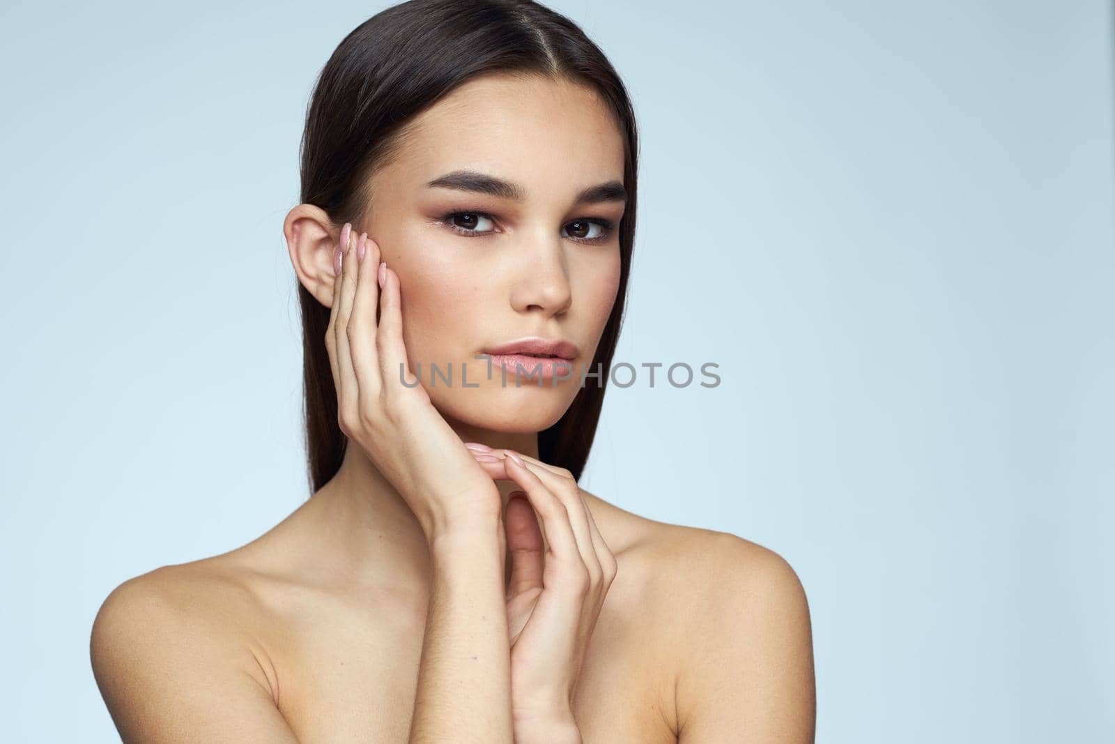 Woman with naked shoulders long hair clean skin cropped view blue background. High quality photo