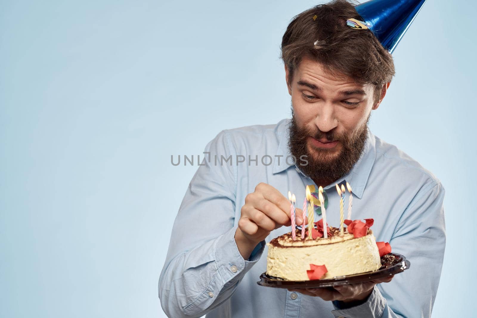 A man in a shirt with a cake in his hands and a festive cap on his head. High quality photo
