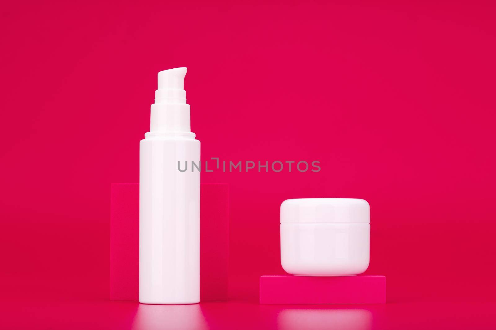 Cosmetic set with face cream or gel and under eye serum or cream against pink background. Concept of daily skin care routine or anti aging skin treatment