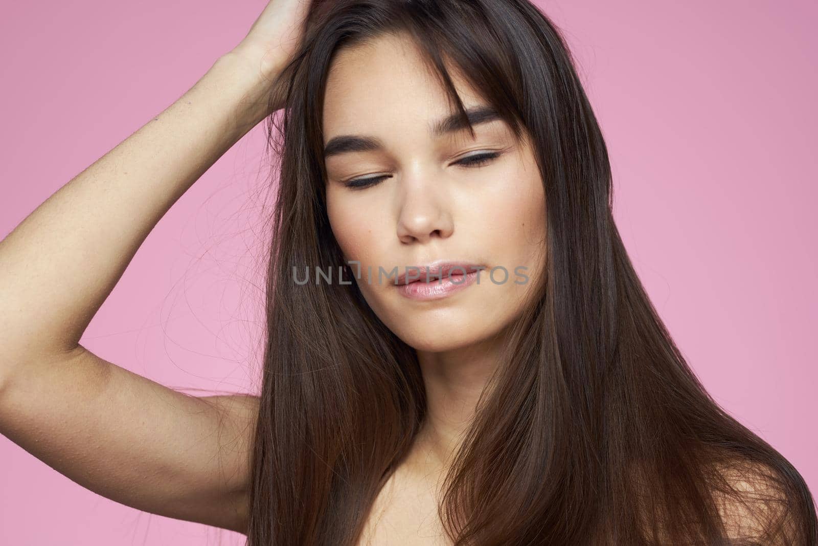 Pretty brunette naked shoulders clear skin pink background. High quality photo