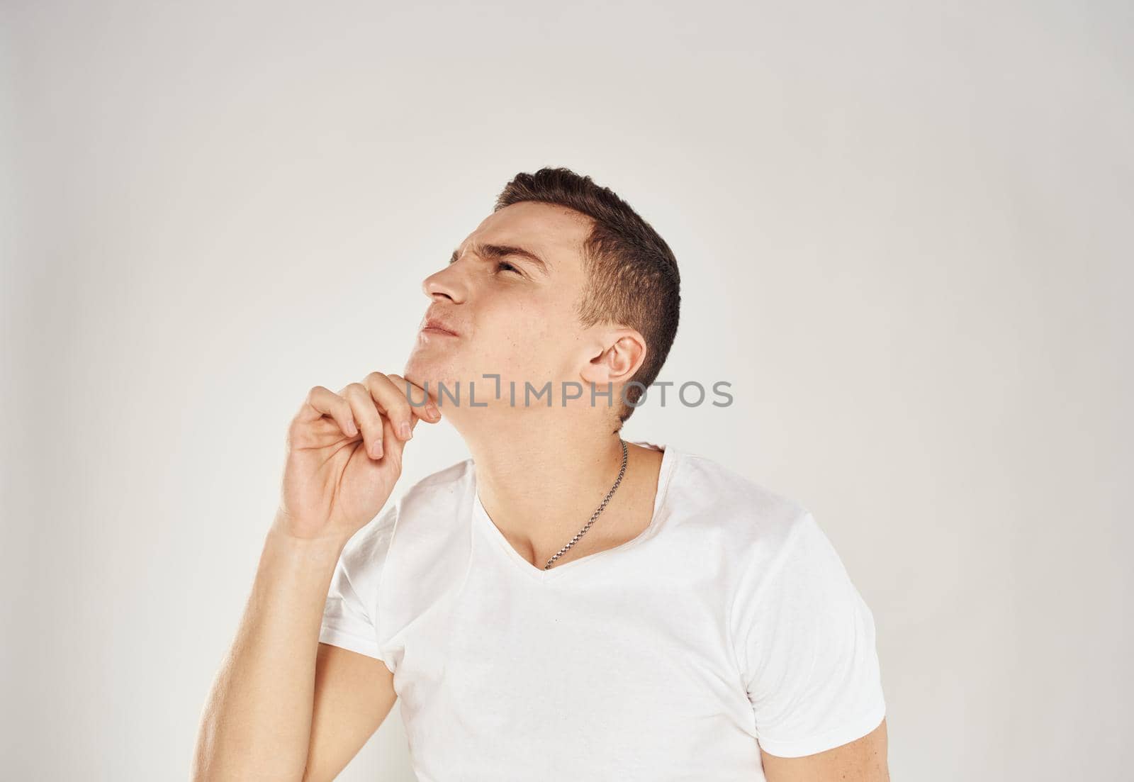 Portrait of a pensive man in a white T-shirt side view light background. High quality photo