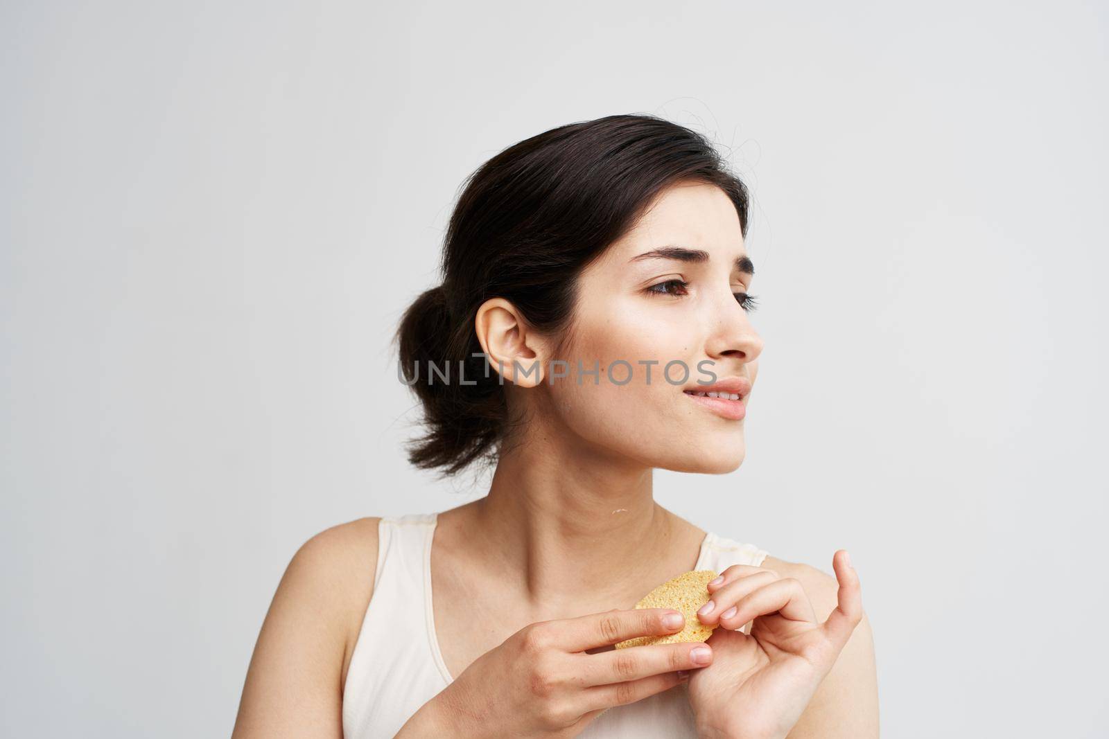 Beautiful brunette holding a sponge in her hands clean health skin close-up. High quality photo
