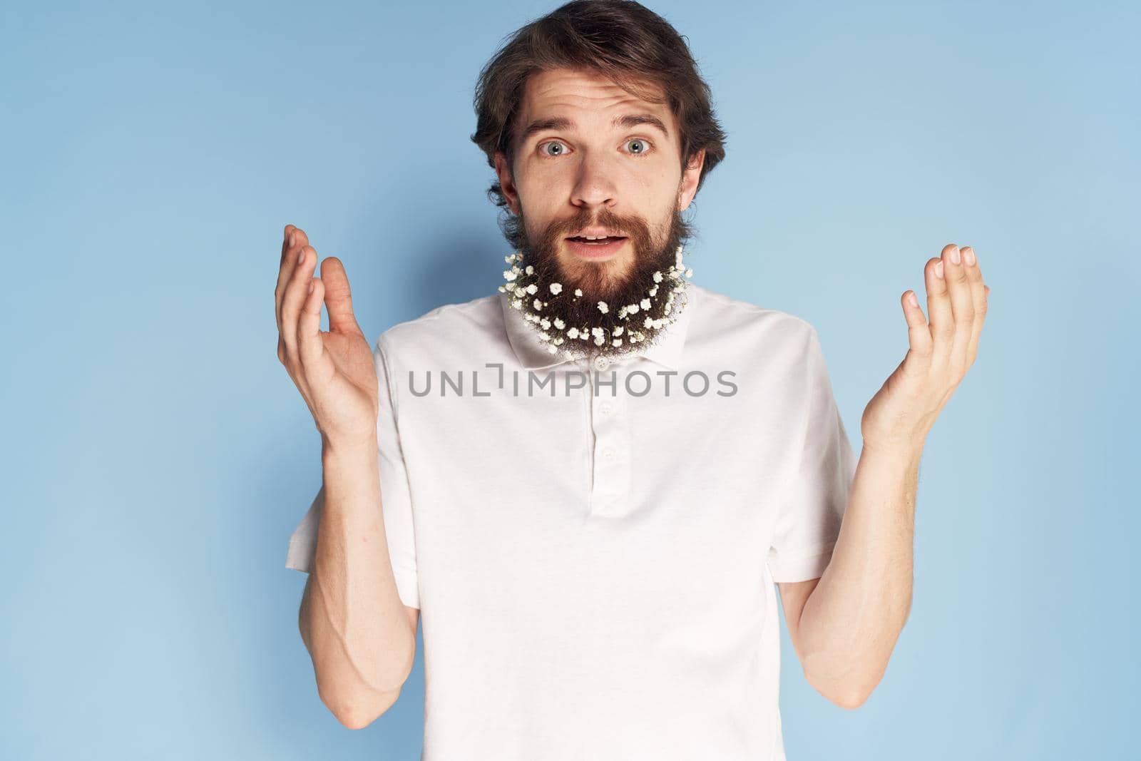 Cheerful car white T-shirt flowers in a beard close-up blue background. High quality photo