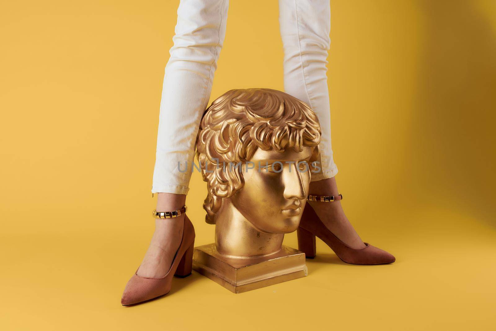 Female feet head sculptures golden color luxury yellow background. High quality photo