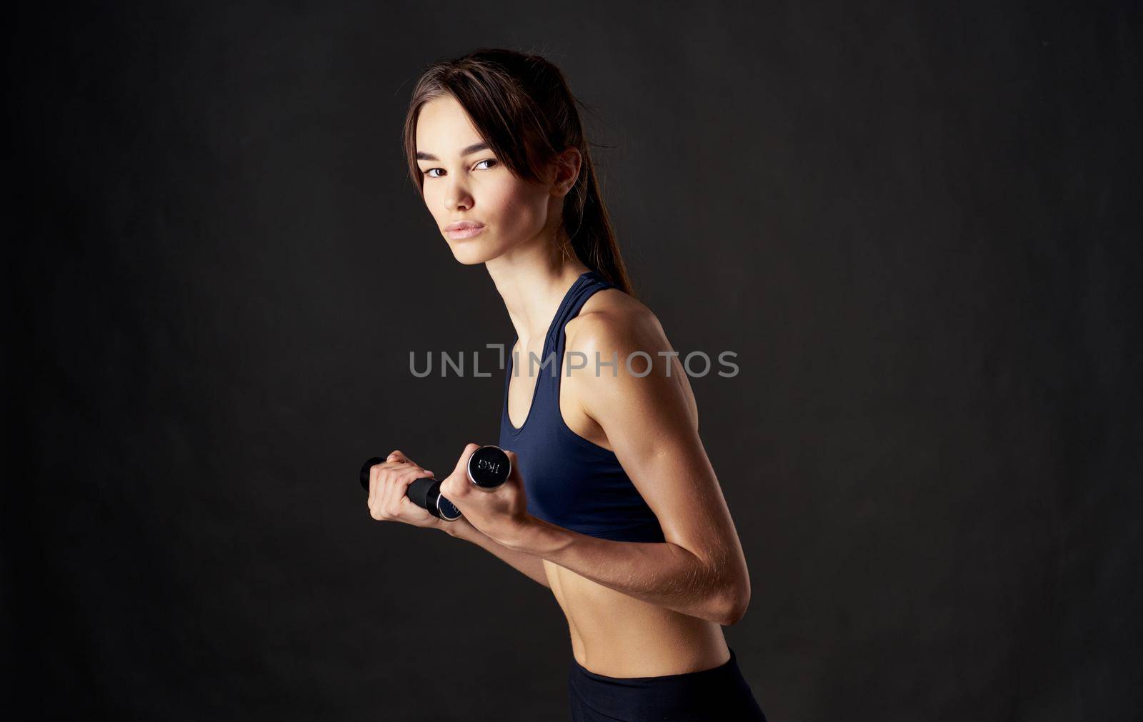 sports woman with dumbbells on a dark background fitness slim figure model. High quality photo