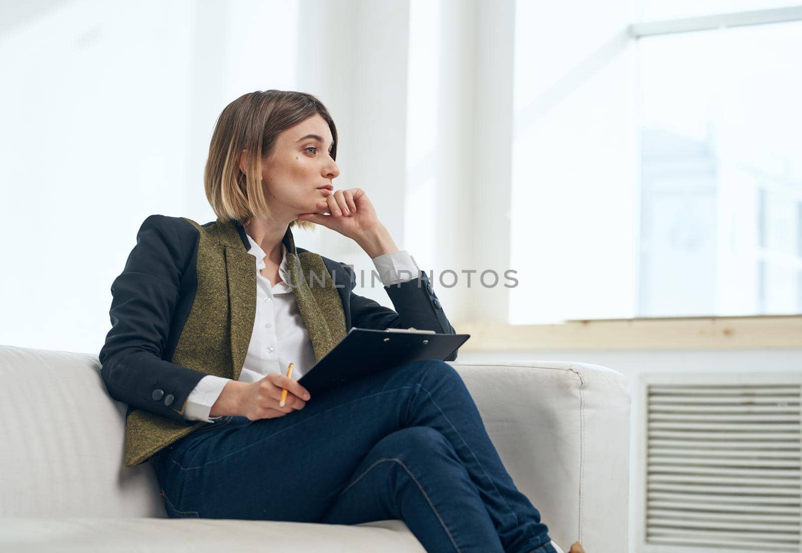Business woman in suit with documents sitting on sofa indoors. High quality photo