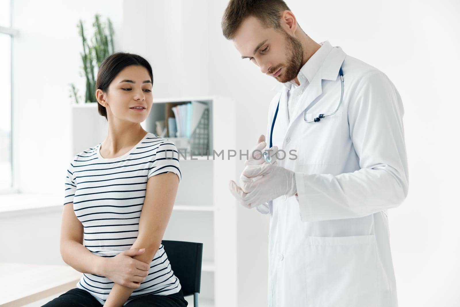 male doctor with a vaccine in his hands next to a hospital patient by SHOTPRIME