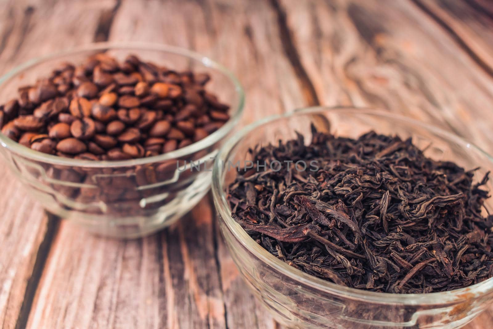 Brewed tea and coffee grains in a glass container on a wooden table close up