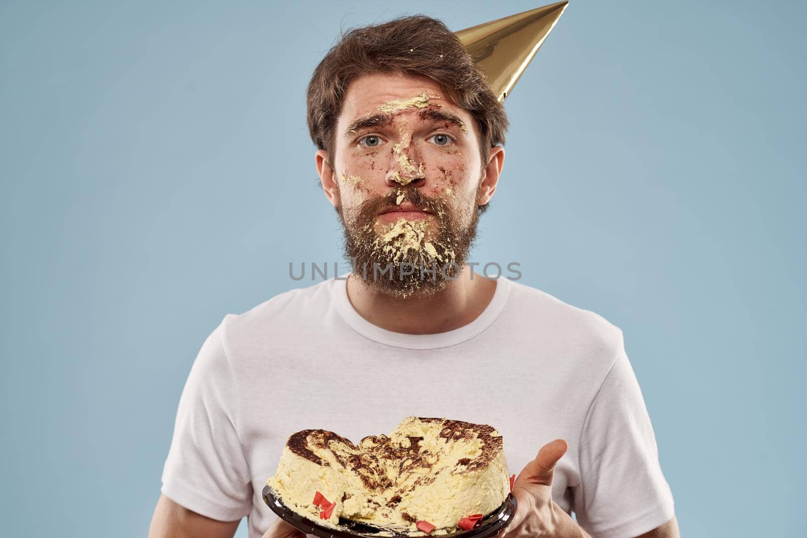 Bearded man in a holiday cap Birthday cake emotions. High quality photo