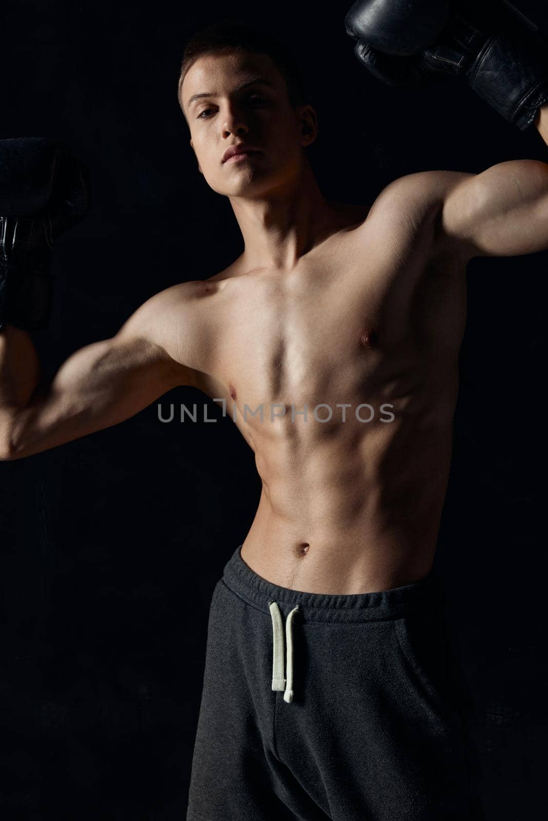 guy with a pumped-up torso gesturing with his hands on a black background boxing gloves fitness. High quality photo