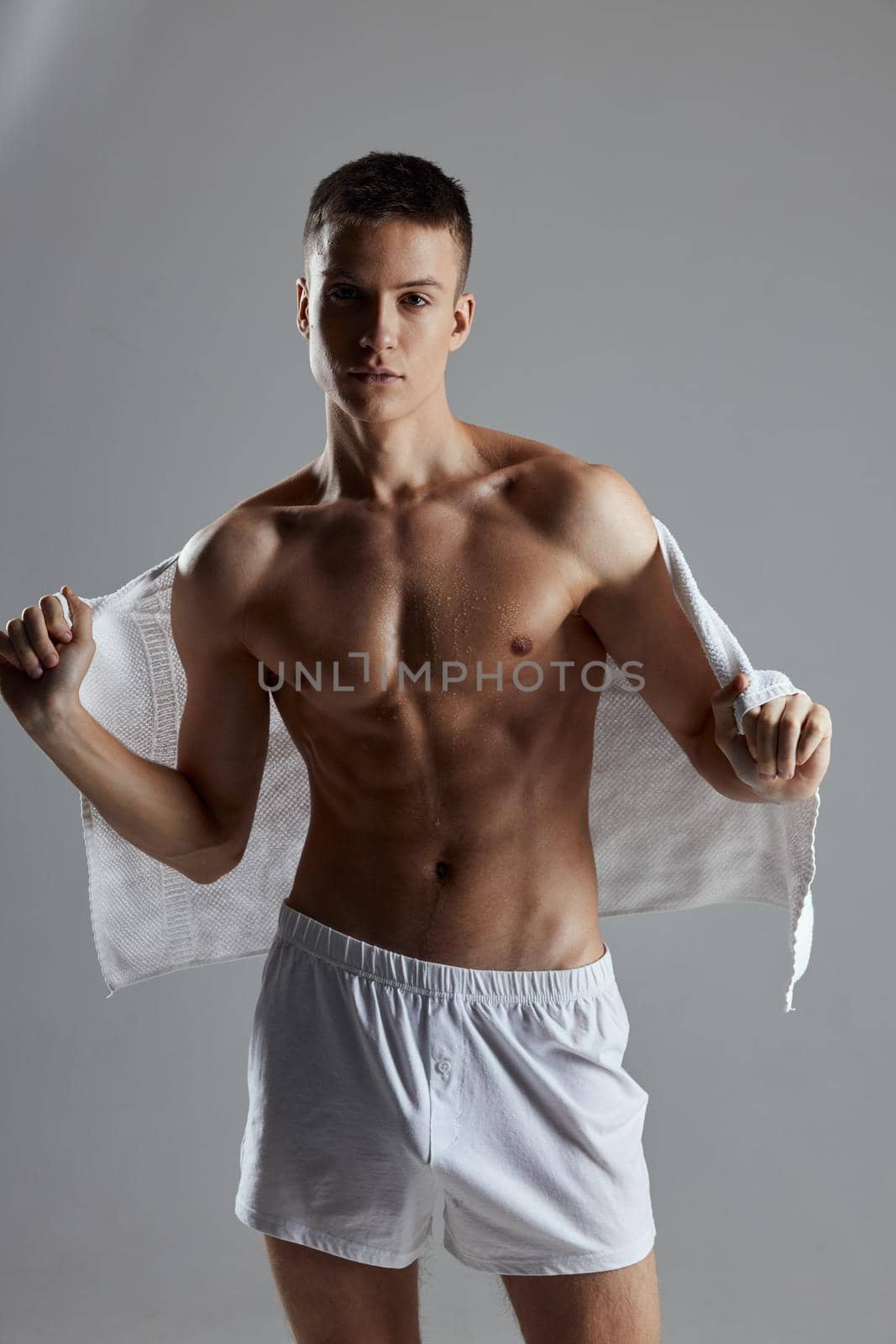 sporty man with muscular torso towel on back white shorts Studio. High quality photo