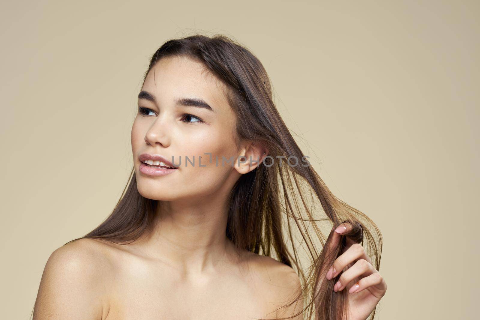 Beautiful brunette naked shoulders skincare beige background. High quality photo