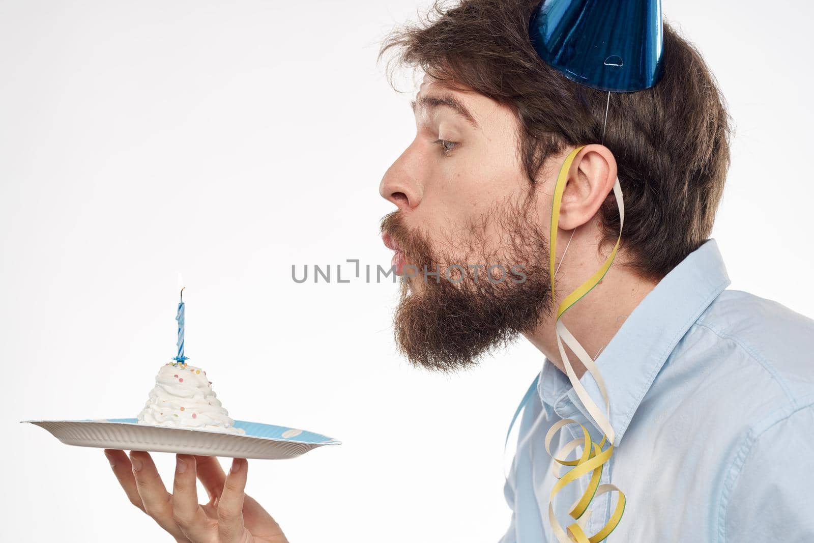 A man with a cake plate and in a blue shirt on a light background birthday party corporate cap. High quality photo