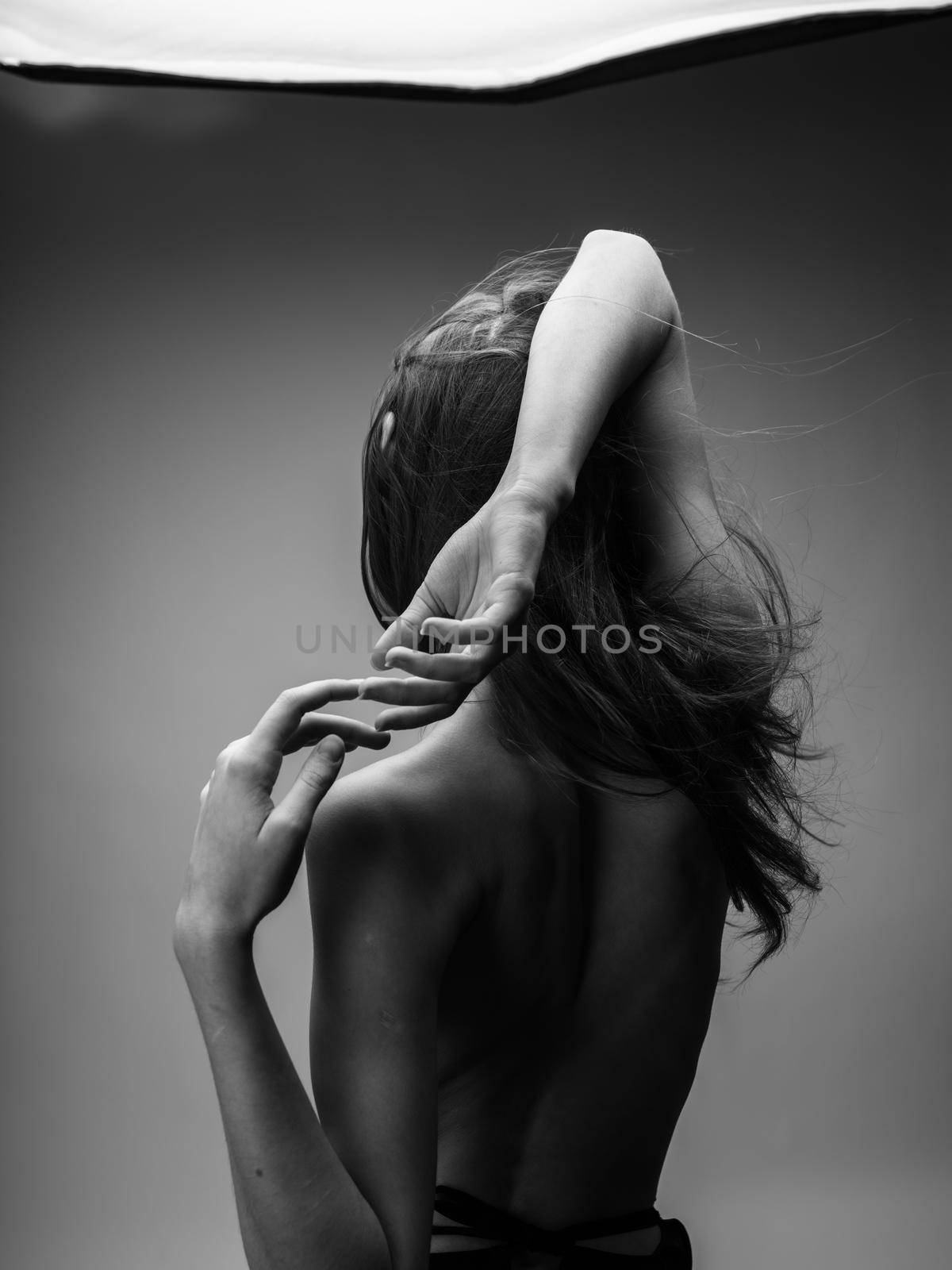 Back view of nude woman with loose hair in black and white photograph. High quality photo