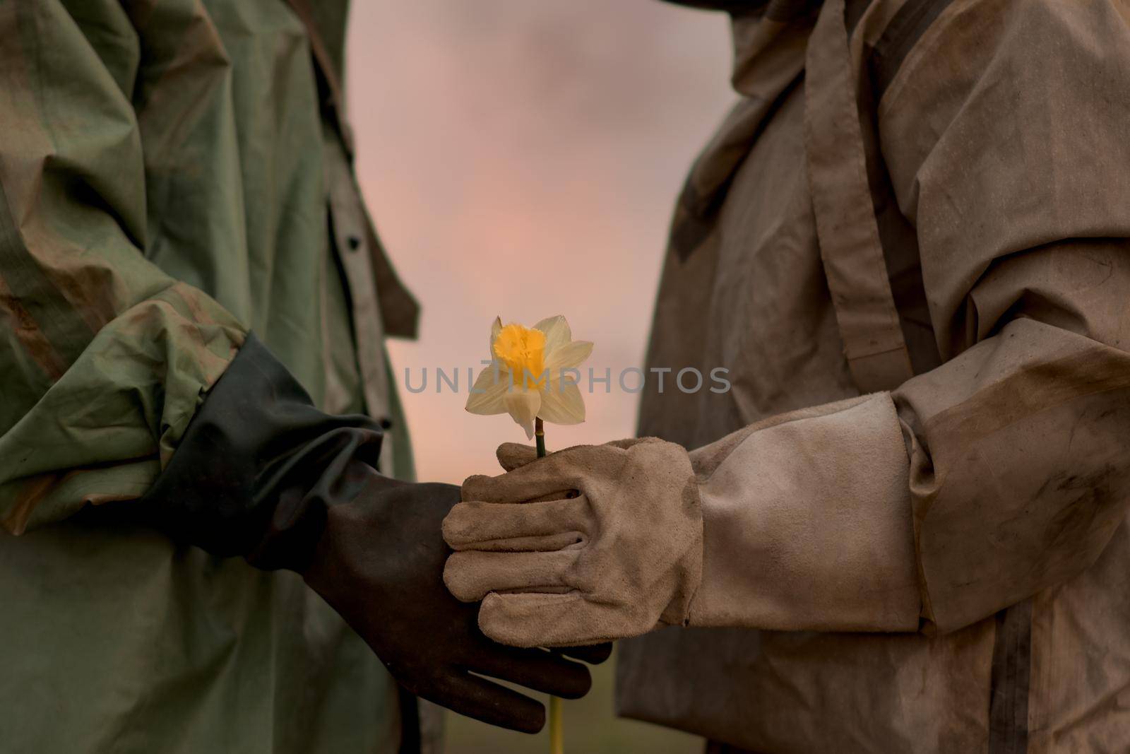 A man and a woman in a chemical protection suit. A man gives a flower to his woman. Post-apocalypse. The world after the atomic war and radiation contamination. Alone on the whole planet.