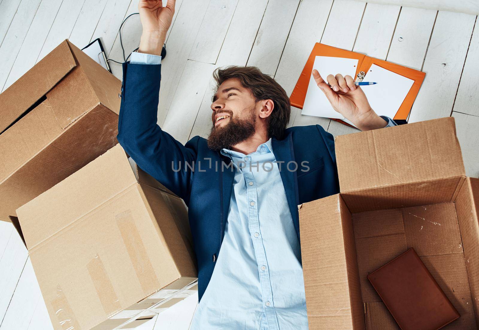 Business man lies on the floor with boxes with things unpacking office professionals. High quality photo