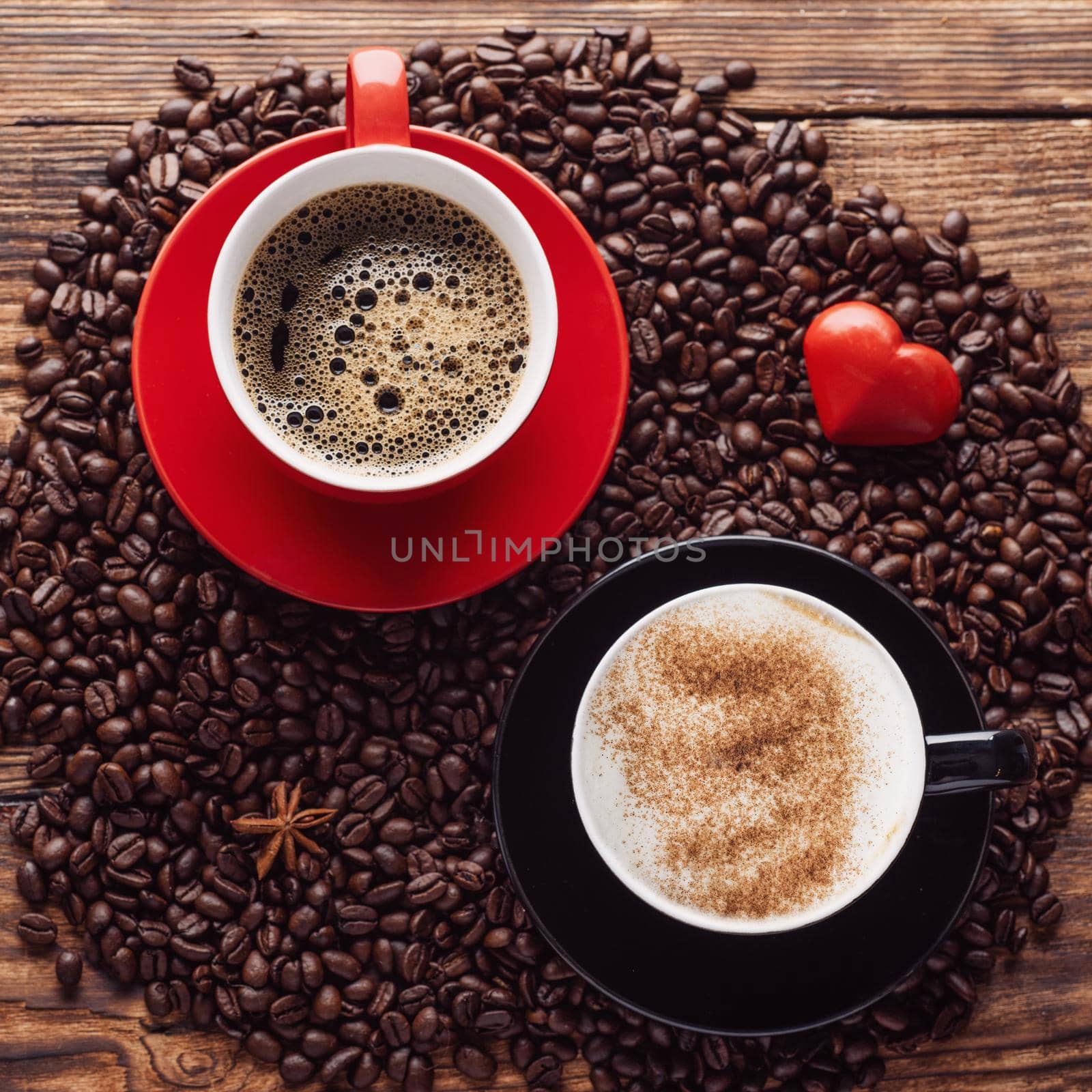 red and black cups of coffee, heart, beans on a wooden backgroun by Iryna_Melnyk
