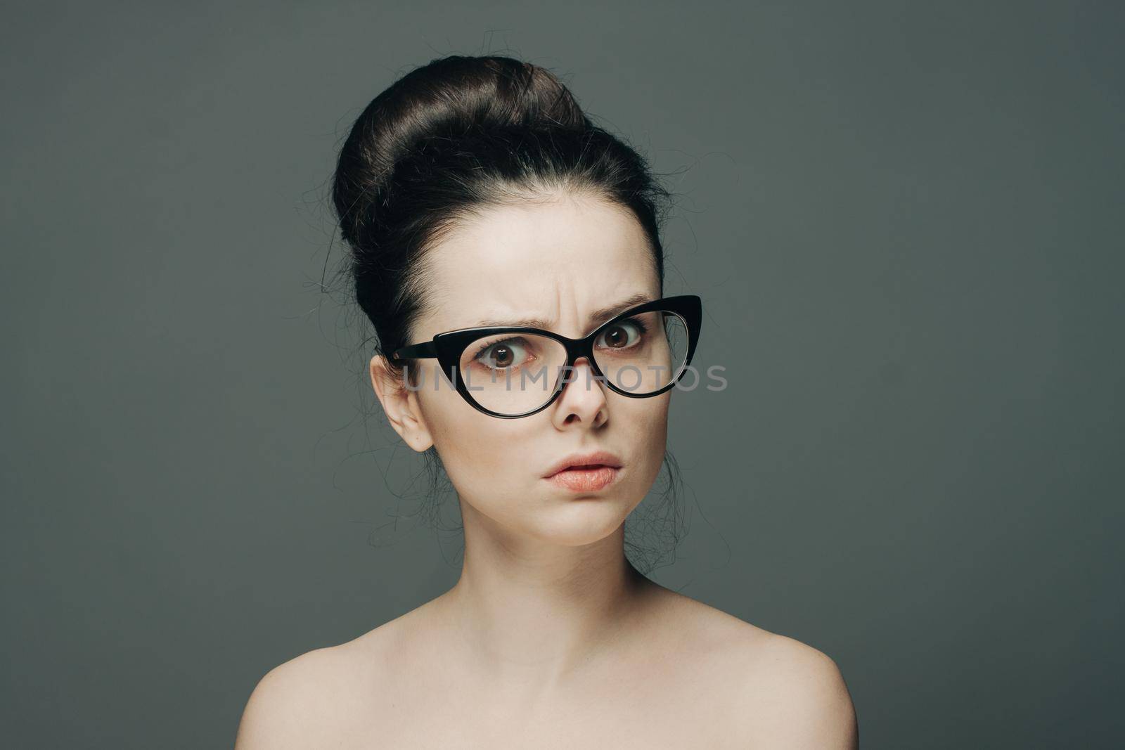 pretty woman naked shoulders gathered hair glasses emotions. High quality photo