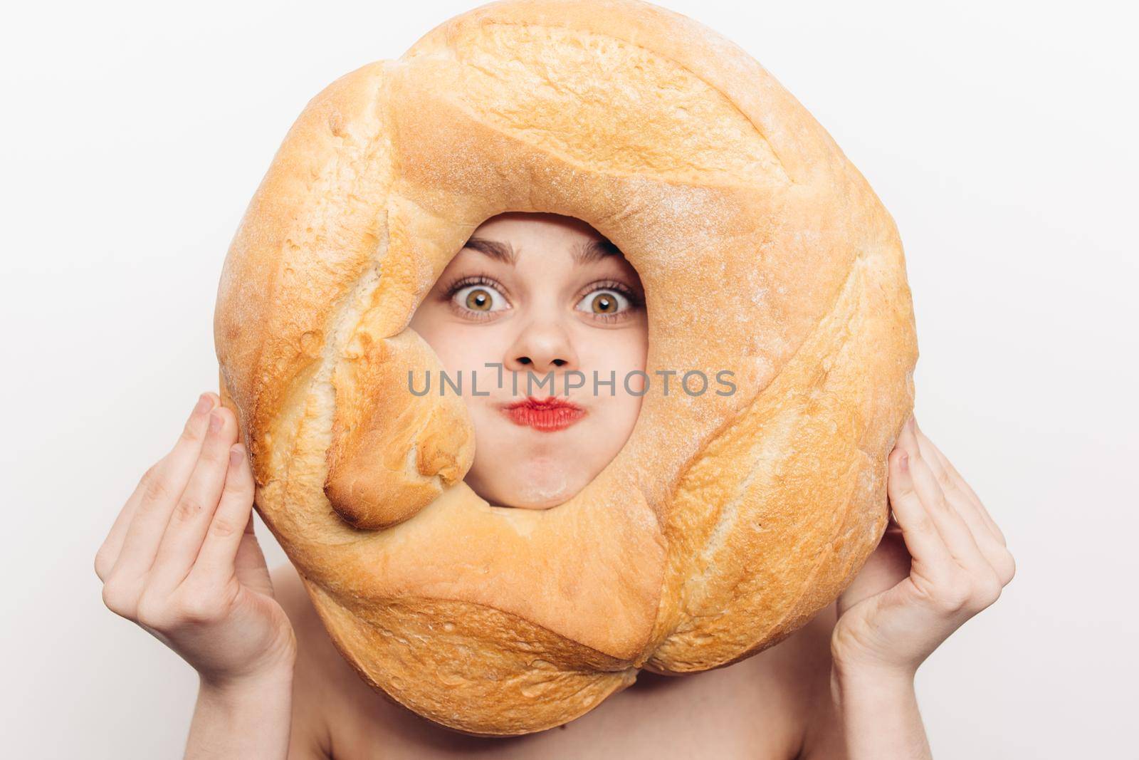 energetic woman grimaces and holds a round loaf of bread in front of her face. High quality photo