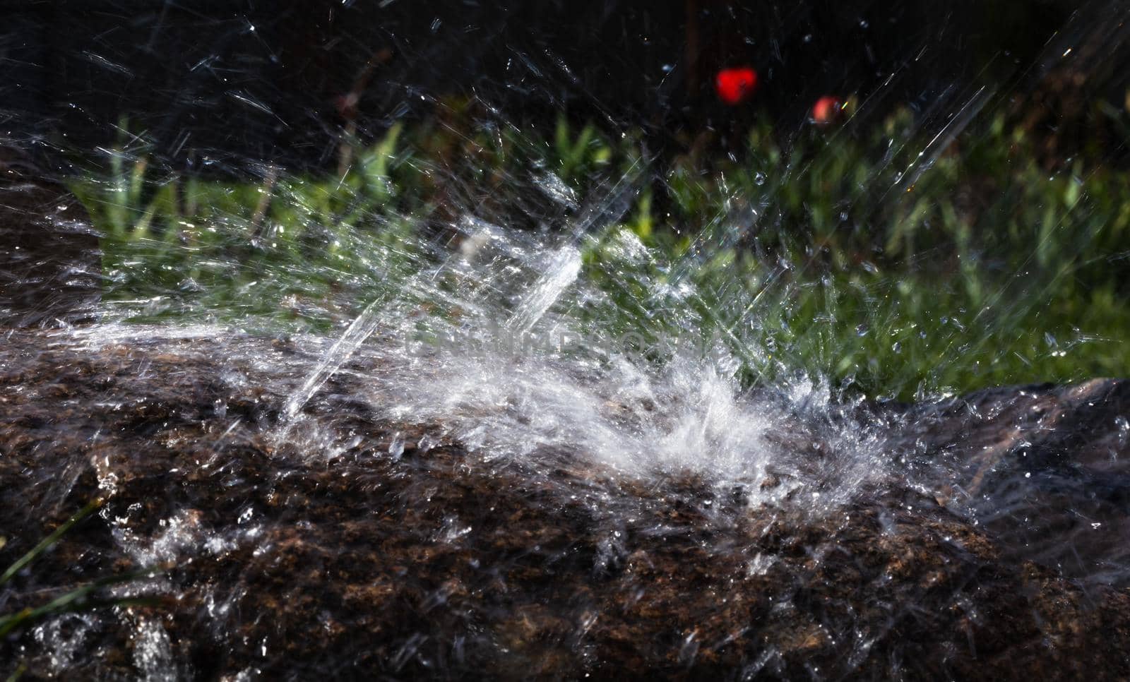Wet stone in the rain. Rain water drop falling to the stone. Water is flowing and splashing around them.