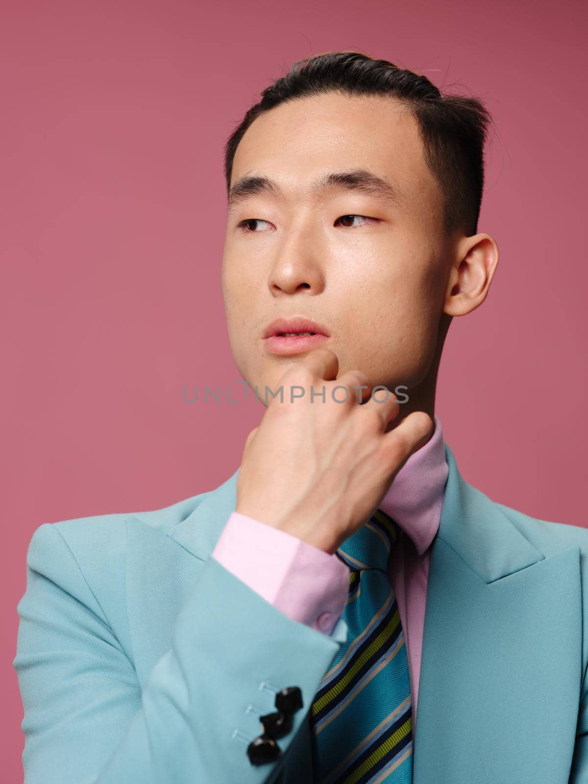 Man asian appearance close-up blue suit pink background emotions. High quality photo