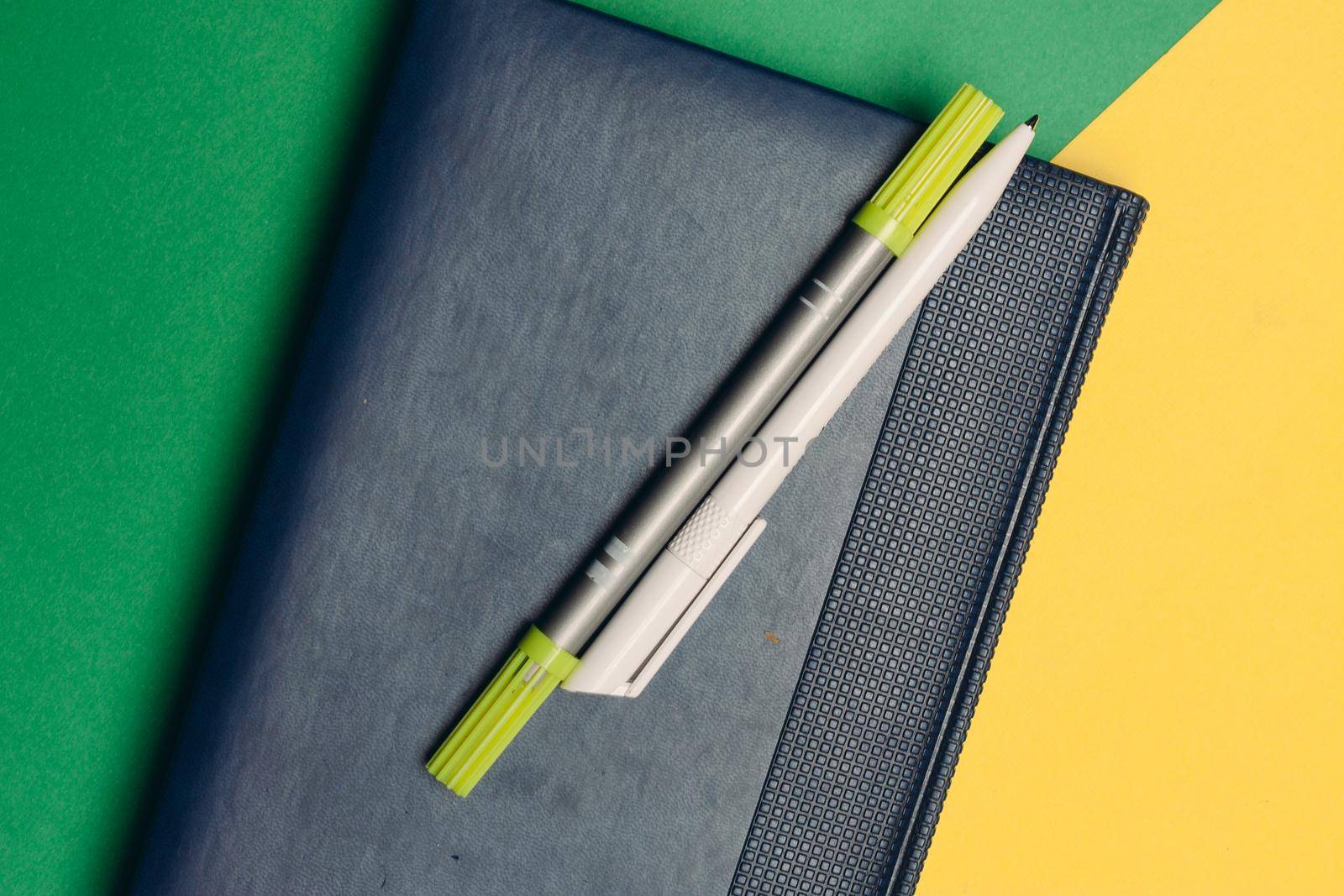 notepad with markers and pens on yellow green background and office supplies codespace. High quality photo