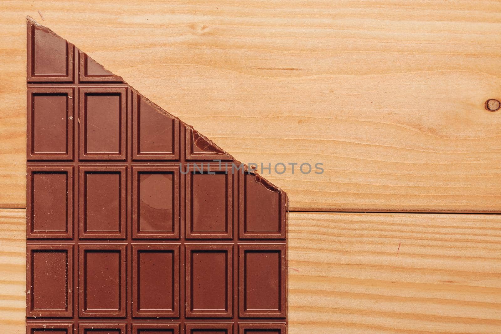 brown chocolate bar cut diagonally on wooden background. High quality photo