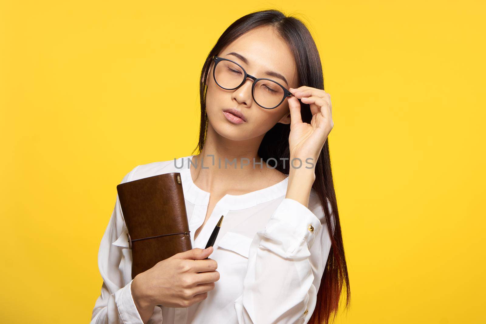 Business woman in glasses holding notepad in hands official yellow isolated background by SHOTPRIME